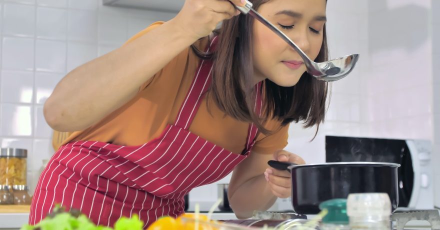 Young Asian woman cooking in kitchen at home.